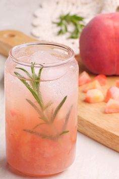 a glass filled with ice and water next to sliced peaches on a cutting board