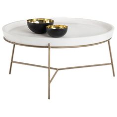 two black bowls on a white table with gold trim around the edges and metal legs