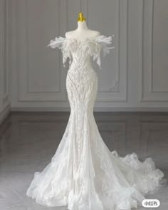 a white wedding dress on a mannequin in front of a wall and floor