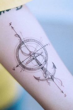 a woman's arm with an arrow and compass tattoo on the left inner forearm