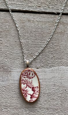 a white and red porcelain pendant on a chain