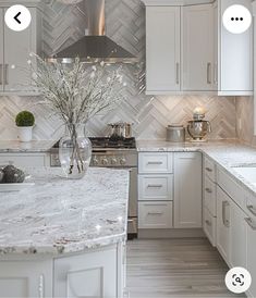 a kitchen with white cabinets and marble counter tops