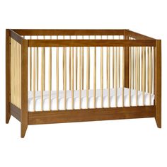 a wooden crib with white sheets on it