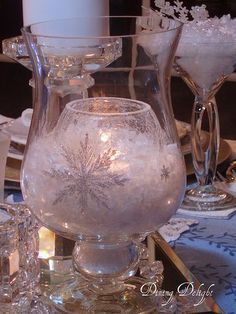 a glass vase filled with snowflakes on top of a table