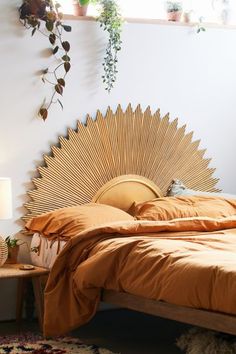 a bed with an orange bedspread in a bedroom next to a plant filled wall