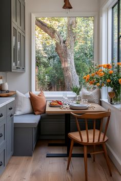 a kitchen with a window seat next to a table and flowers in vases on the windowsill