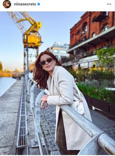 a woman leaning on a railing next to a body of water with a crane in the background