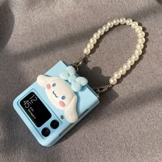 a cell phone with a cute little bear on it's cover and a chain attached to it