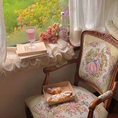 a chair sitting in front of a window next to a book