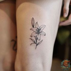 a woman's thigh with a small flower tattoo on her left side ribcage