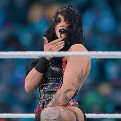 a woman with black hair and tattoos on her face holding a microphone in front of an audience