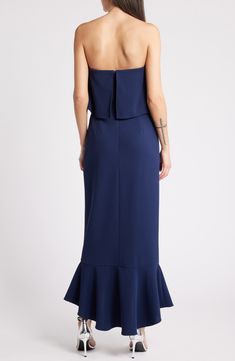 the back of a woman wearing a dark blue dress with ruffles on it