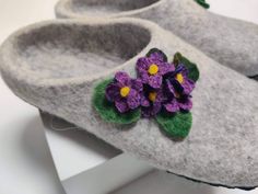 a pair of gray slippers with purple flowers on the inside and green leaves on the outside