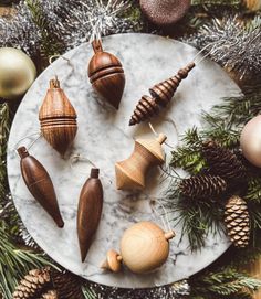 christmas ornaments on a marble plate surrounded by pine cones and fircone garlands