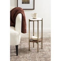 a white chair sitting next to a table with a coffee cup on top of it