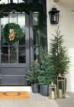 front door decorated with evergreen wreaths and potted pine trees for christmas or new year's eve