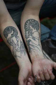 two people holding hands with tattoos on their arms