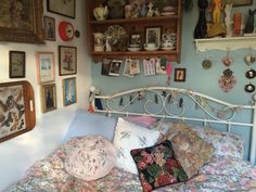 a bed with lots of pillows and pictures on the wall