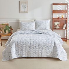 a bed with blue and white bedspread in a room next to a chair