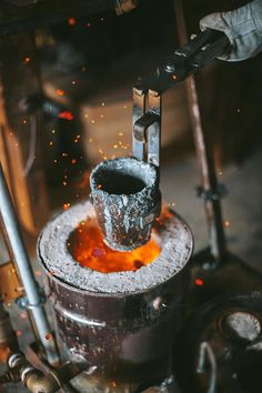 an orange substance is being poured into a metal container with tongs and other tools in the background