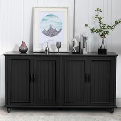 a black sideboard with two wine glasses on top and a vase next to it