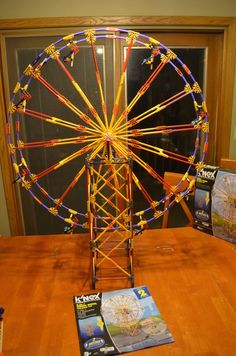 a ferris wheel made out of legos sitting on top of a wooden table next to magazines