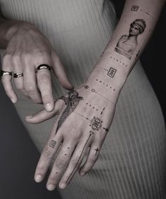 two people holding hands with tattoos on their fingers and wrist, both showing different symbols