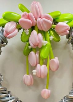 a bunch of pink and green flowers hanging from a wall