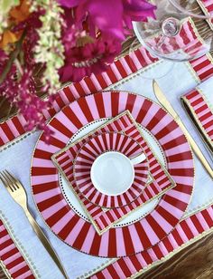 red and white striped place setting with gold trimmings on the edges, along with pink flowers