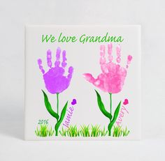 two handprinted flowers with the words we love grandma written on them in pink and purple