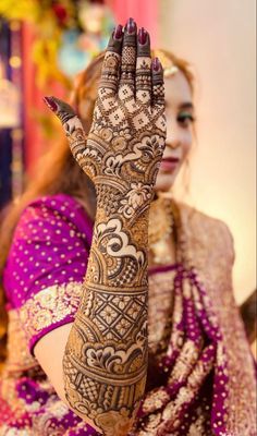 a woman is holding her hands up with hendi tattoos on it's arms