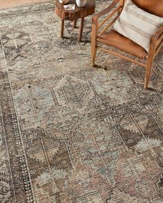 a large rug with an ornate design on the floor and two chairs in front of it