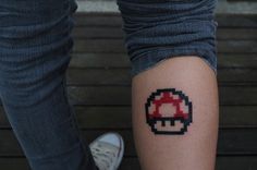 a close up of a person's leg with a mario mushroom tattoo on it