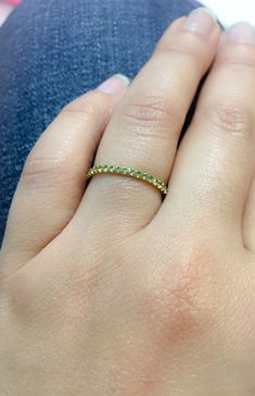 a woman's hand with a gold ring on her left hand and green stones in the middle