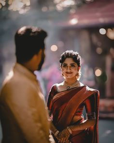 a woman in a red sari standing next to a man