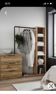 an open wardrobe with clothes hanging on the rack and next to it is a bed