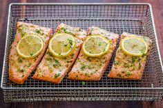 four pieces of salmon on a cooling rack with lemons and parsley garnish