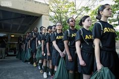 a group of young women standing next to each other wearing army shirts and carrying bags