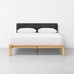 a bed with two pillows on top of it and a wooden frame in the middle