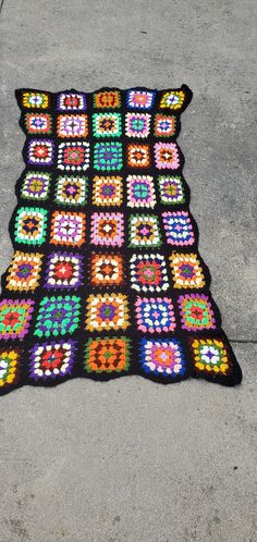 a crocheted blanket is laying on the sidewalk