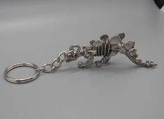 a metal keychain with a small toy dinosaur on it's back end