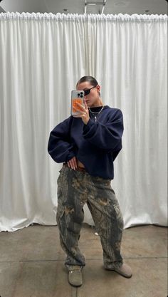 a man taking a selfie in front of a white curtain with his cell phone