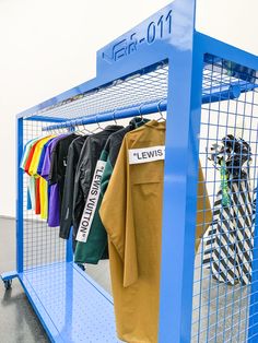 a blue rack with shirts hanging on it's sides and another item in the background