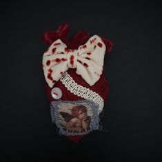 a red and white knitted hat with an angel on it's side, attached to a string