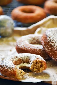 powdered sugar covered donuts sitting on top of parchment paper