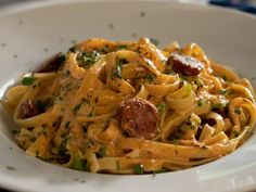 a white plate topped with pasta and sausage