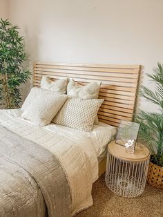 a bedroom with a bed, side table and potted plants