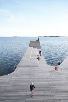 people are walking along the pier near the water