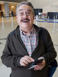 an older man with glasses and a mustache is holding a cell phone in his hand