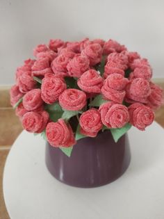 a purple vase filled with pink flowers on top of a table